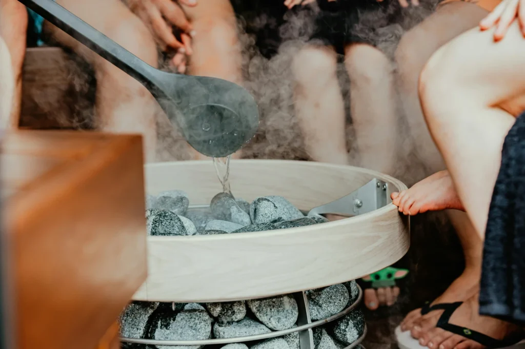 a sauna user pours water on sauna rocks