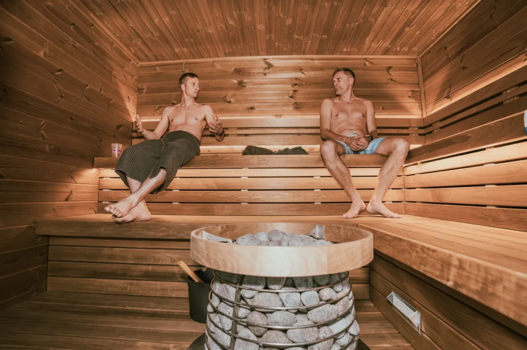 two adults sitting in a traditional Finnish sauna